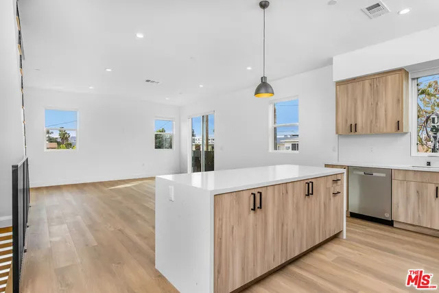 a kitchen that has a lot of white cabinets and wooden floor