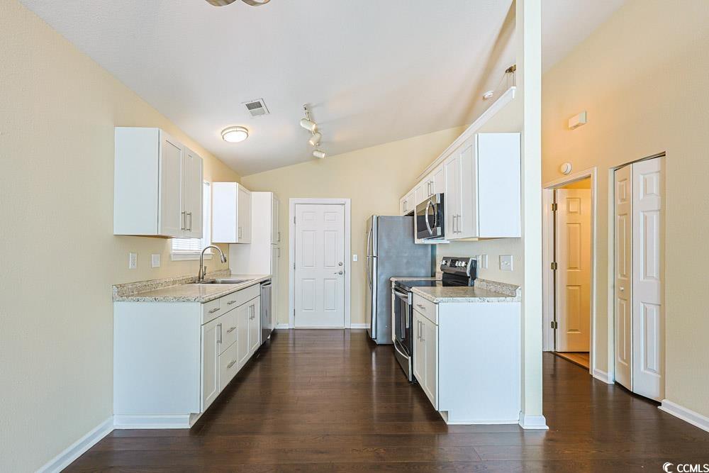 833 Silvercrest Drive Myrtle Beach, SC 29579 - Photo 6 of 30 Kitchen featuring vaulted ceiling, appliances with stainless steel finishes, white cabinets, and dark wood-style flooring