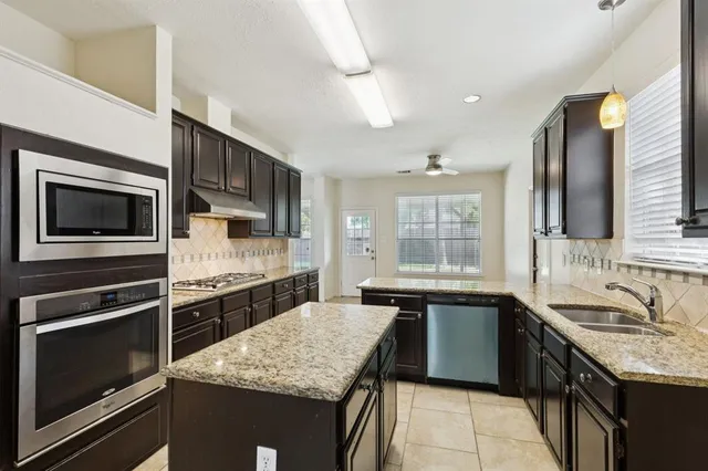 a kitchen with stainless steel appliances kitchen island granite countertop a sink stove and microwave