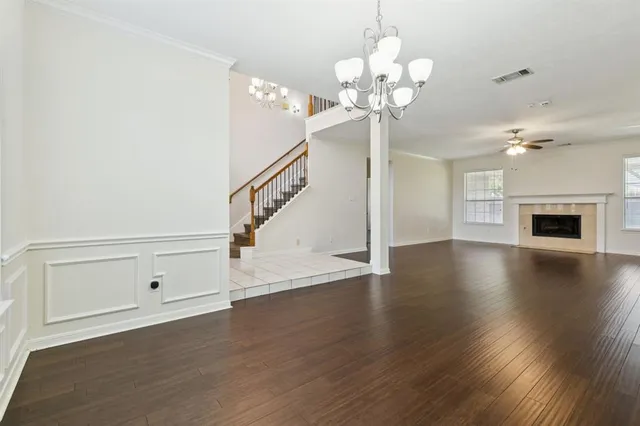 a view of a livingroom with wooden floor staircase and a chandelier