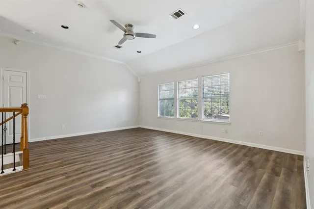 an empty room with wooden floor fan and windows