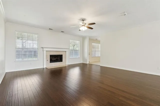 an empty room with wooden floor ceiling fan and windows
