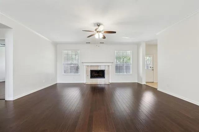 a view of an empty room with wooden floor fireplace and a window