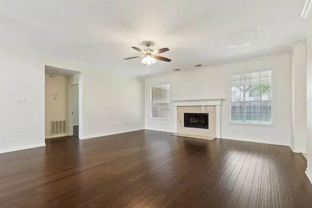 a view of an empty room with wooden floor and a fireplace
