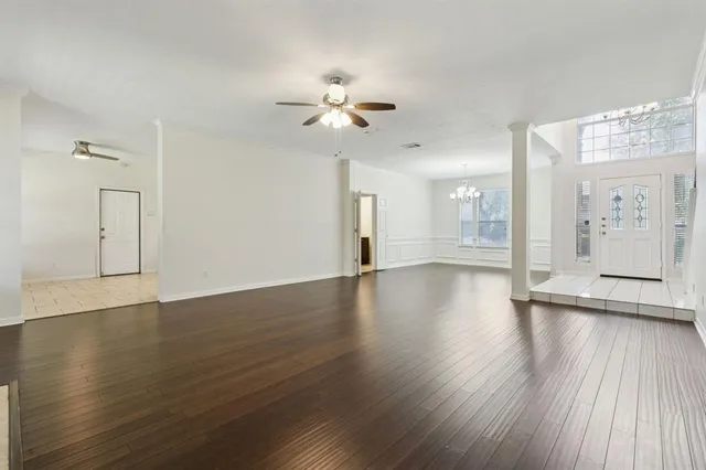 a view of an empty room with wooden floor and a ceiling fan