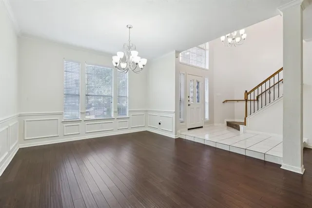 a view of an empty room with wooden floor and staircase