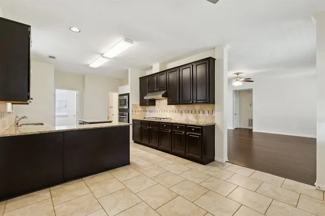 a large kitchen with stainless steel appliances granite countertop a refrigerator and a stove top oven