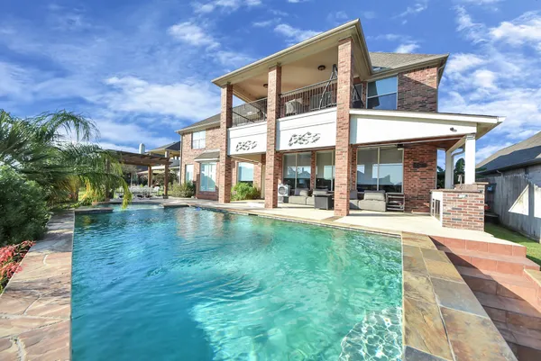 a view of a patio with a table and chairs under an umbrella with large trees