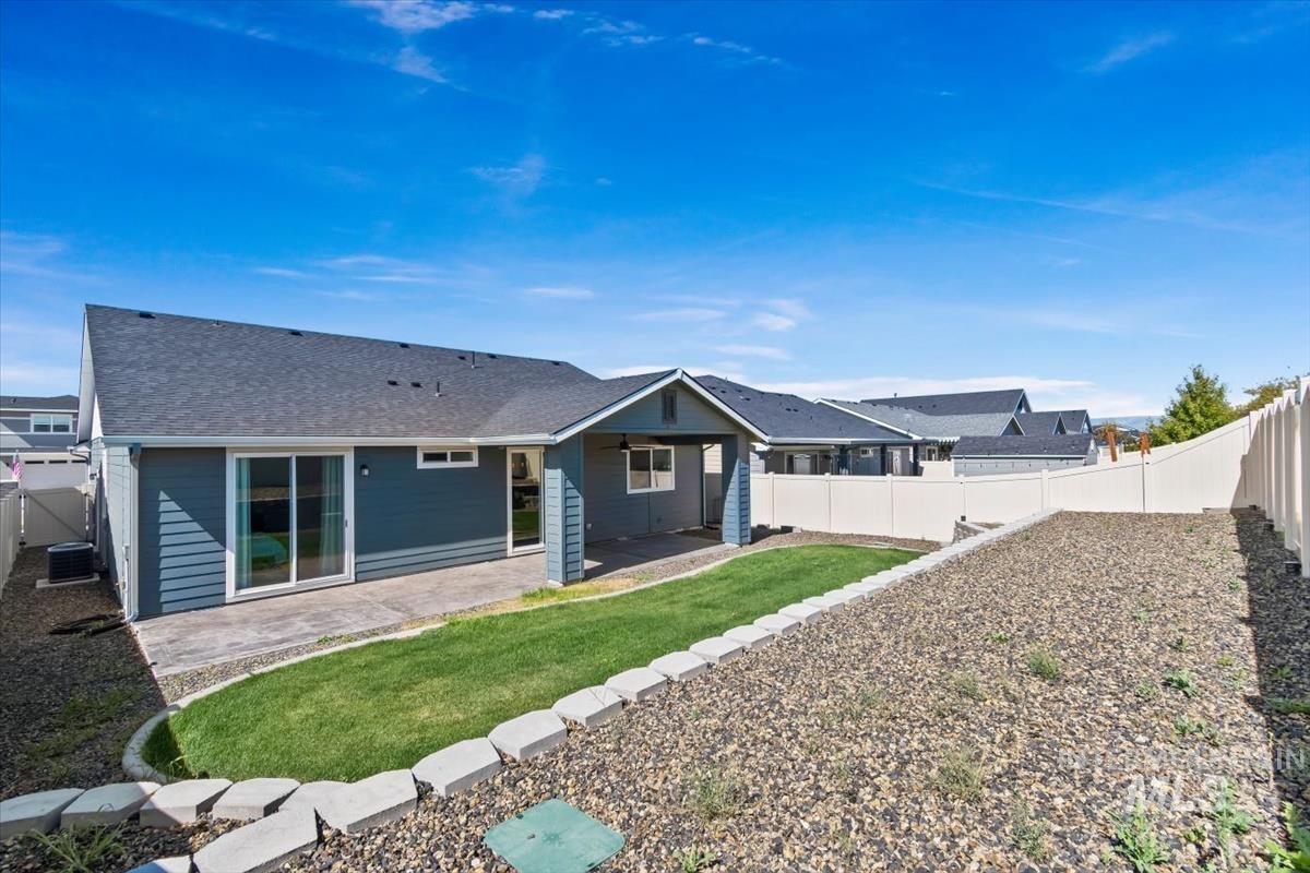 5897 West Riva Capri Street Meridian, ID 83646 - Photo 38 of 50 Spacious backyard featuring a covered patio, concrete patio, sliding glass door access, and a sloped, terraced landscape with a partial privacy fence