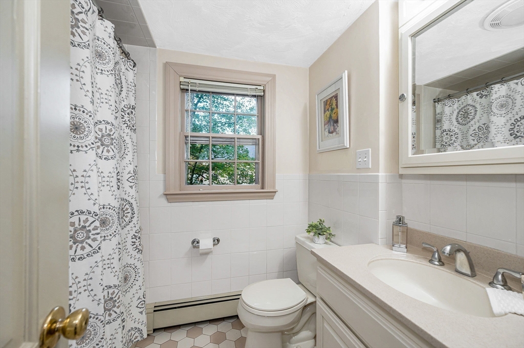 8 Greenwood Road Reading, MA 01867 - Photo 27 of 39 a bathroom with a granite countertop toilet a sink a mirror a window and a shower