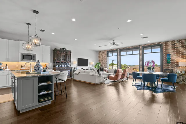 a living room with furniture kitchen view and a wooden floor