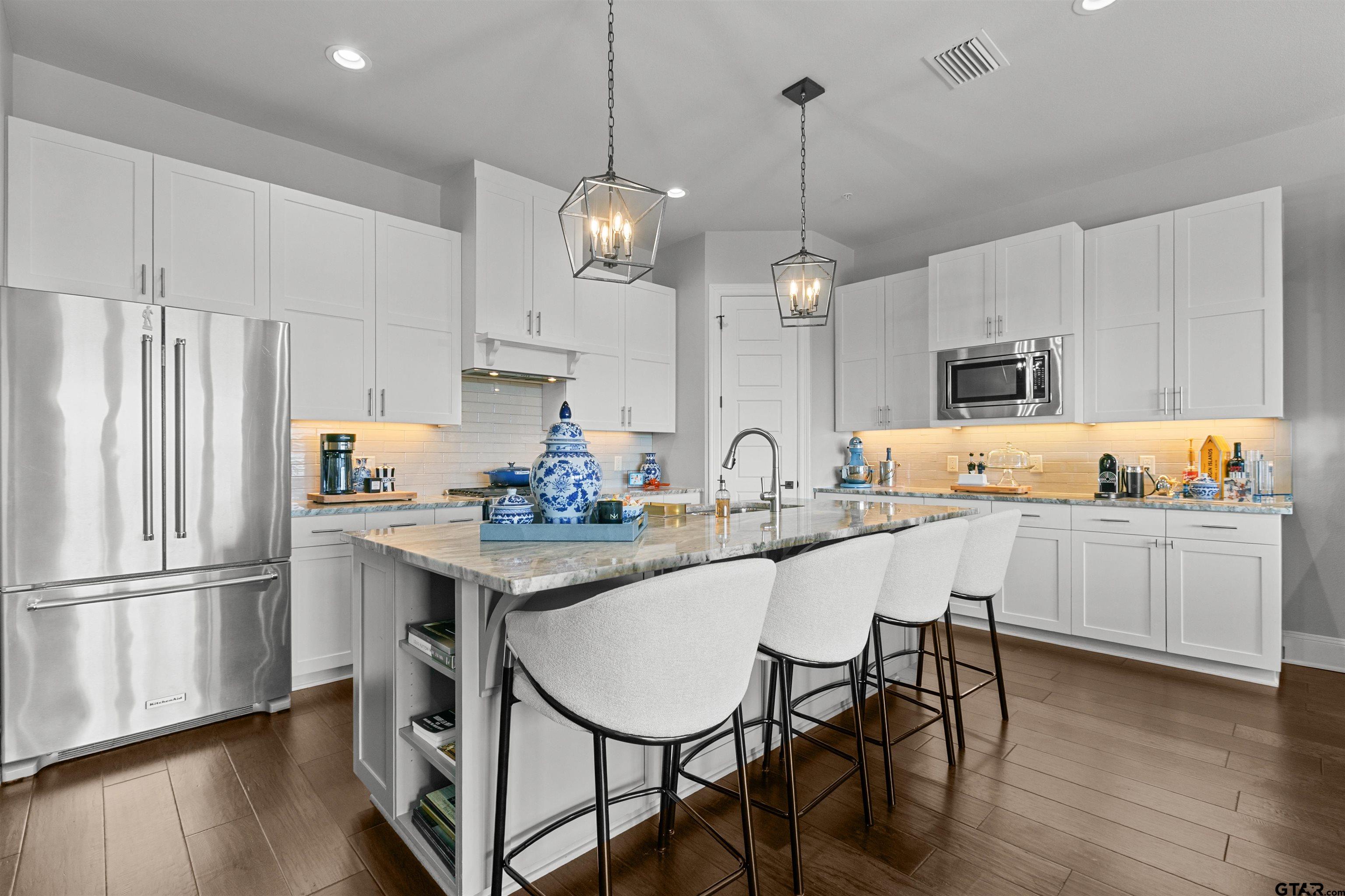 2981 Crest Ridge Drive, Unit 7 Tyler, TX 75703 - Photo 2 of 22 a kitchen with stainless steel appliances a dining table chairs refrigerator and sink