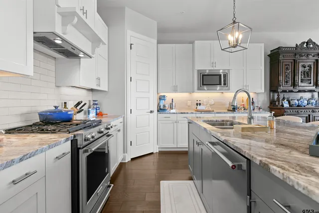 a kitchen with granite countertop a sink stainless steel appliances and cabinets