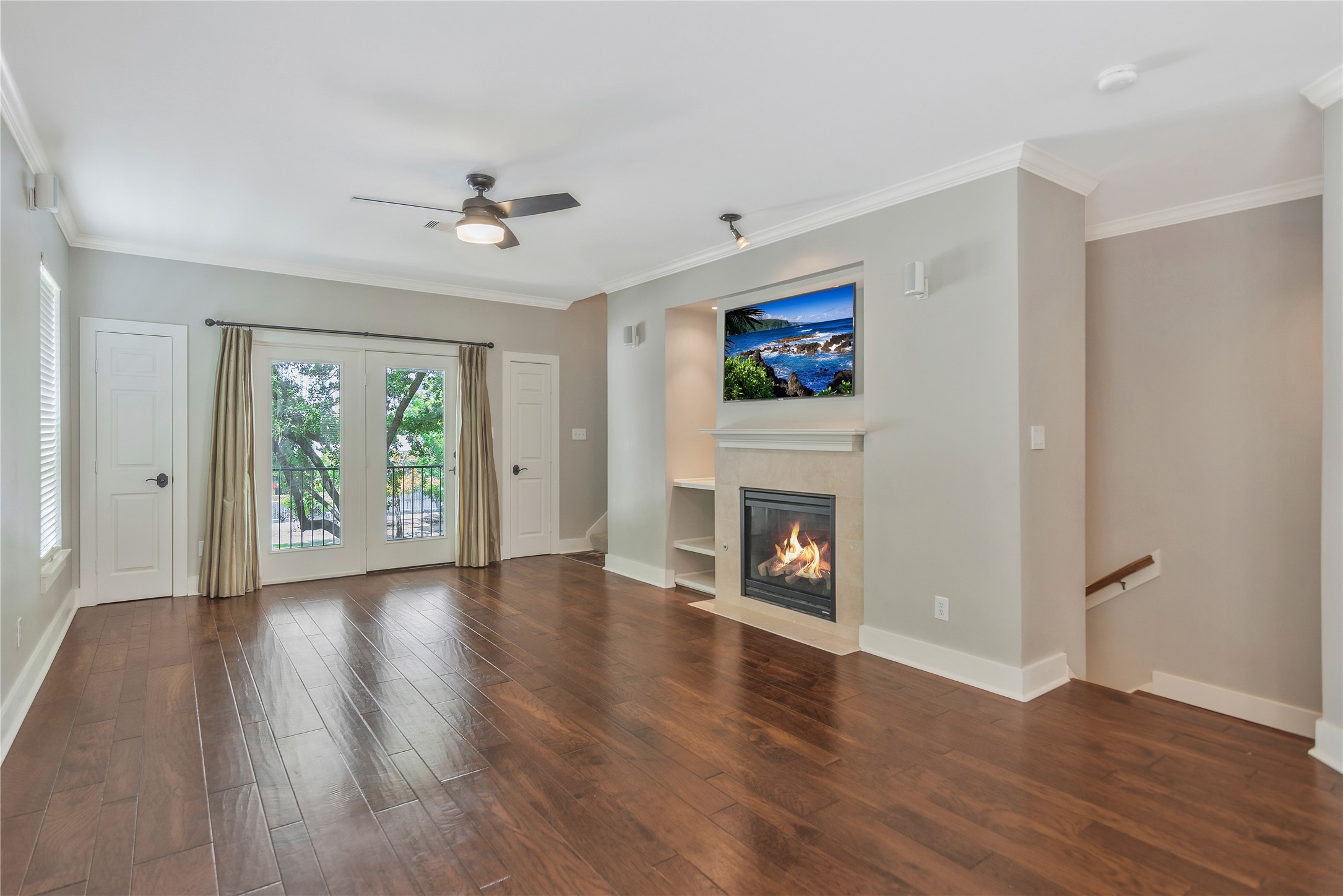 1207 Nagle Street Houston, TX 77003 - Photo 10 of 26 The French doors with curtains open to a balcony, providing natural light and a view of greenery. There's also a ceiling fan for added comfort.