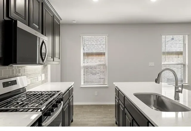 a kitchen with granite countertop a stove a sink and a microwave