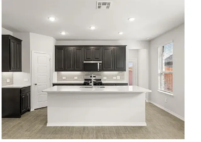 a kitchen with kitchen island granite countertop a sink window and cabinets