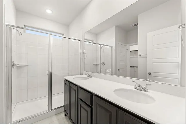 a bathroom with a double vanity sink mirror and shower