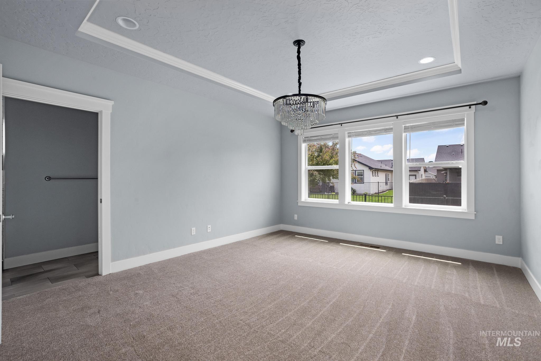 2681 East Rhyolite Court Nampa, ID 83686 - Photo 23 of 48 Spacious room featuring a tray ceiling with recessed lighting, a decorative chandelier, and a triple window assembly