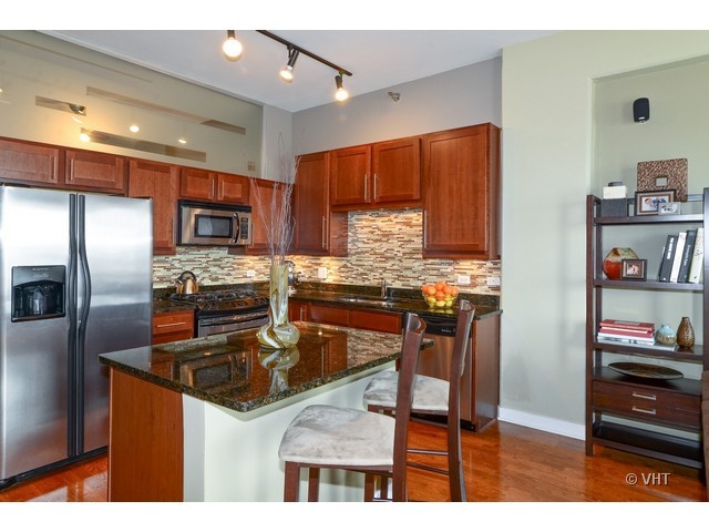 901 West Madison Street, Unit 809 Chicago, IL 60607 - Photo 5 of 12 a kitchen with kitchen island granite countertop a refrigerator stove and oven