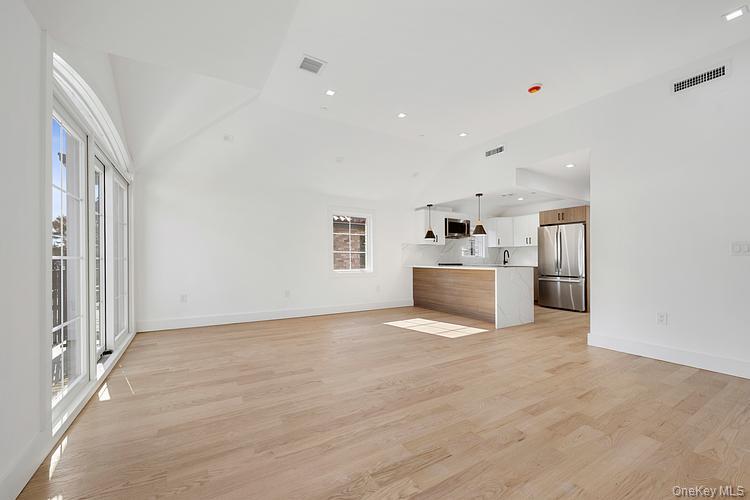 38-40 215th Street Queens, NY 11361 - Photo 20 of 35 Unfurnished living room featuring light wood-style floors, healthy amount of natural light, recessed lighting, and high vaulted ceiling