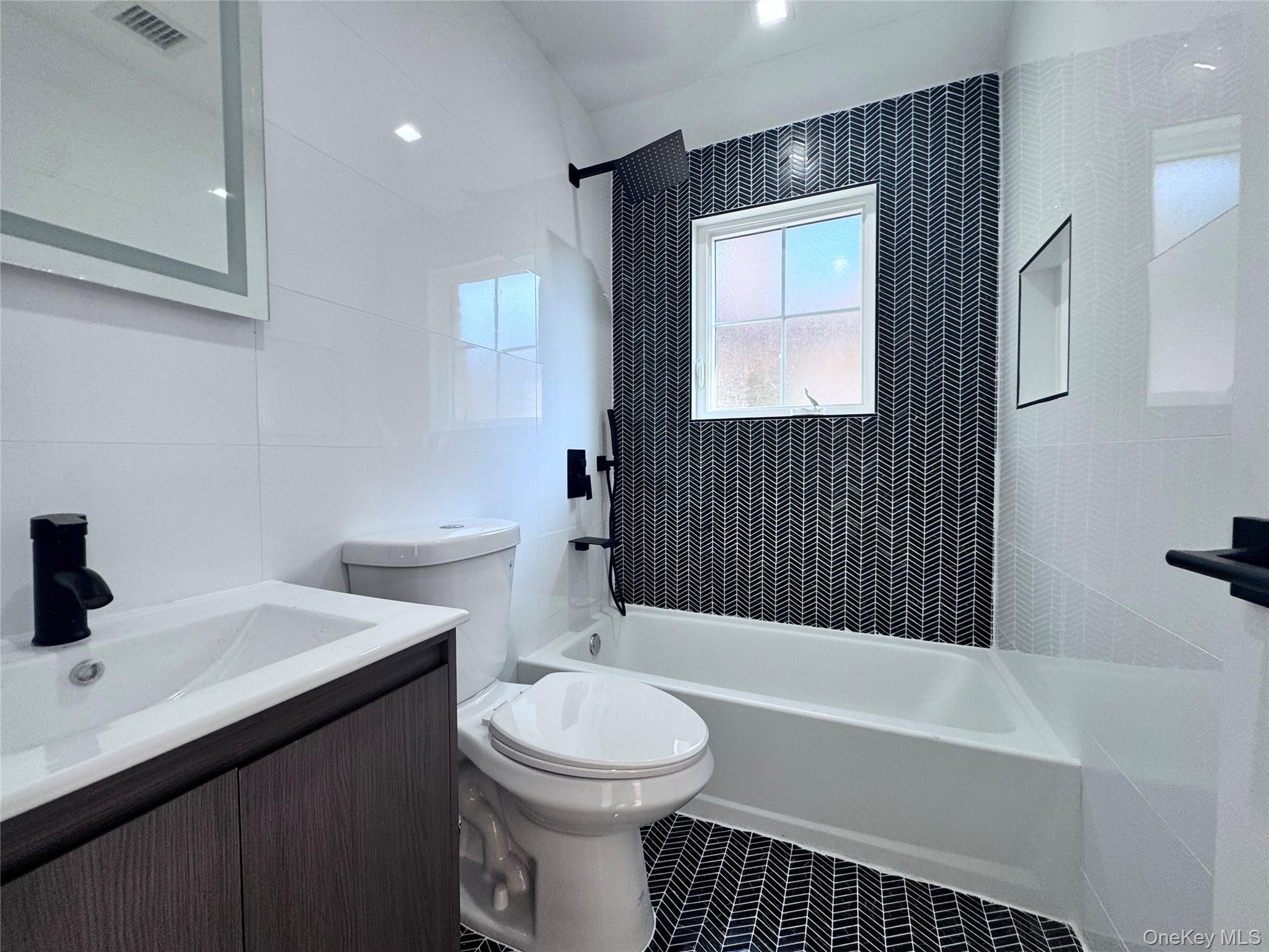 38-40 215th Street Queens, NY 11361 - Photo 6 of 35 Full bath with tub / shower combination, tile walls, vanity, and tile patterned flooring