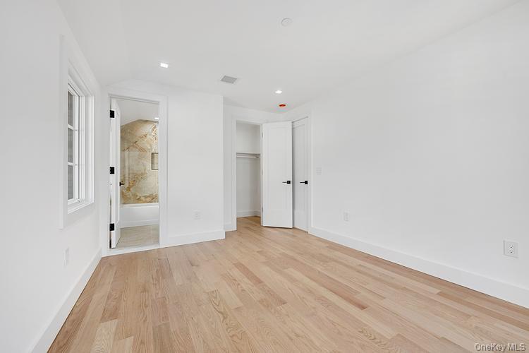 38-40 215th Street Queens, NY 11361 - Photo 10 of 35 Unfurnished bedroom featuring light wood-style flooring, a closet, ensuite bath, and recessed lighting
