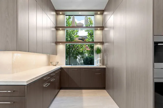 a view of a living room with a floor to ceiling window and kitchen view
