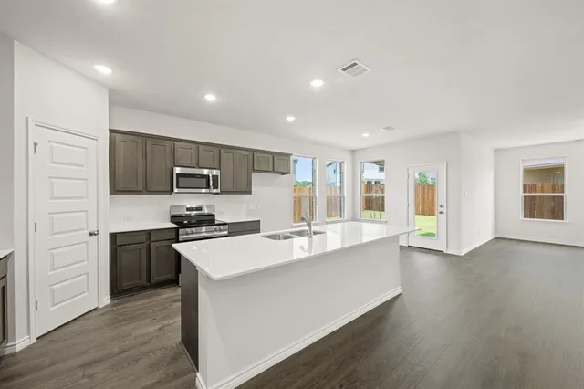 a large kitchen with stainless steel appliances sink a microwave and cabinets
