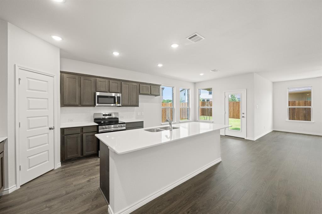 409-411 Saddle Drive Denton, TX 76209 - Photo 6 of 29 a large kitchen with kitchen island a stove a sink a refrigerator and cabinets