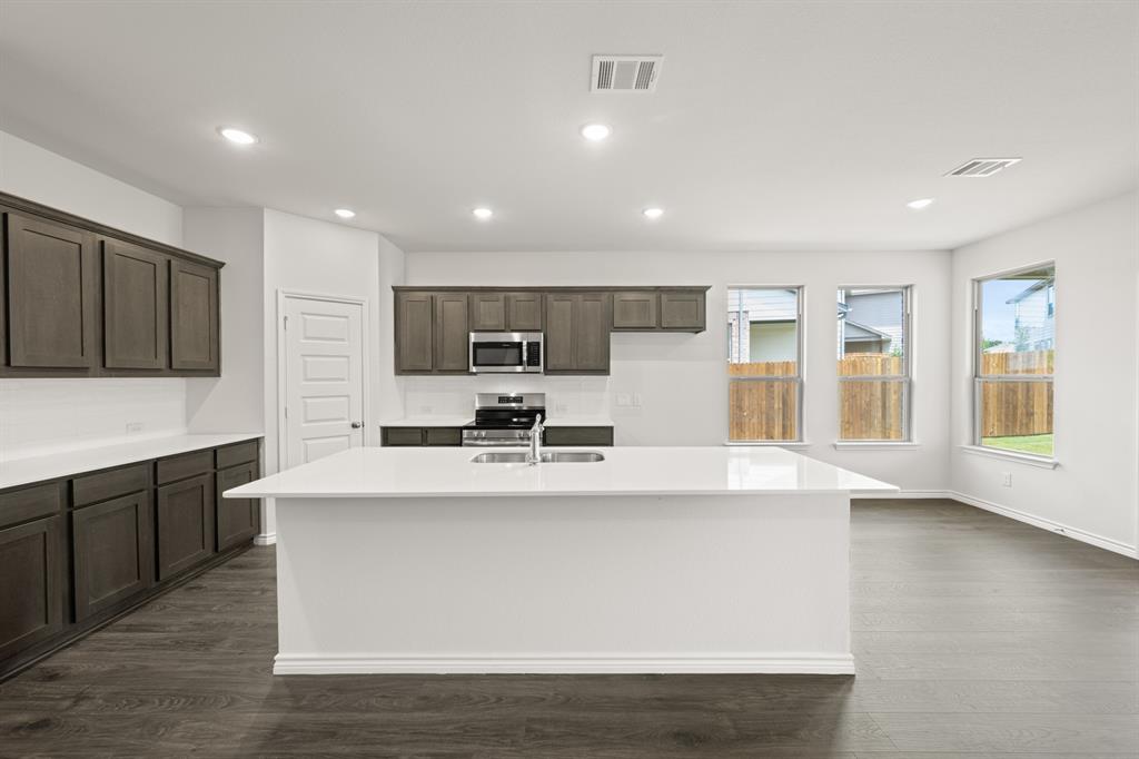 409-411 Saddle Drive Denton, TX 76209 - Photo 7 of 29 a large kitchen with stainless steel appliances a large counter top a stove a refrigerator cabinets and a center island