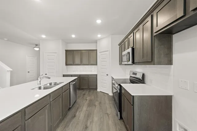 a view of a kitchen with a sink wooden cabinets and a refrigerator