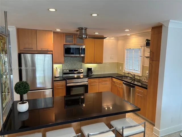 a kitchen with stainless steel appliances granite countertop a refrigerator a sink a stove and white cabinets