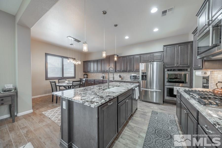 2285 Trakehner Lane, Unit NV Reno, NV 89521 - Photo 6 of 23 a kitchen with stainless steel appliances granite countertop a stove top oven a refrigerator oven and white cabinets