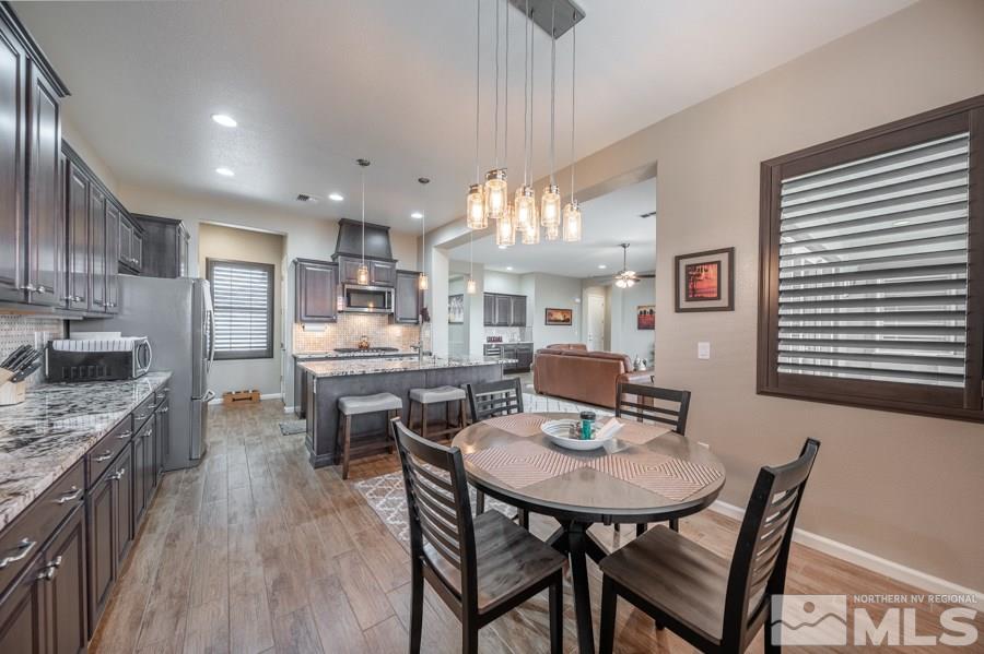 2285 Trakehner Lane, Unit NV Reno, NV 89521 - Photo 8 of 23 a kitchen with stainless steel appliances kitchen island granite countertop a kitchen island hardwood floor sink stove dining table and chairs