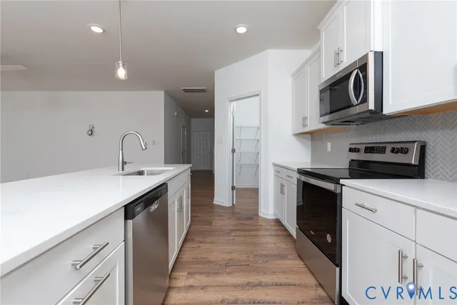 a kitchen with stainless steel appliances granite countertop a sink a stove top oven and refrigerator