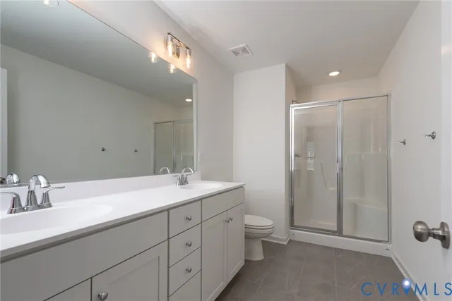 a spacious bathroom with a double vanity sink toilet mirror and shower