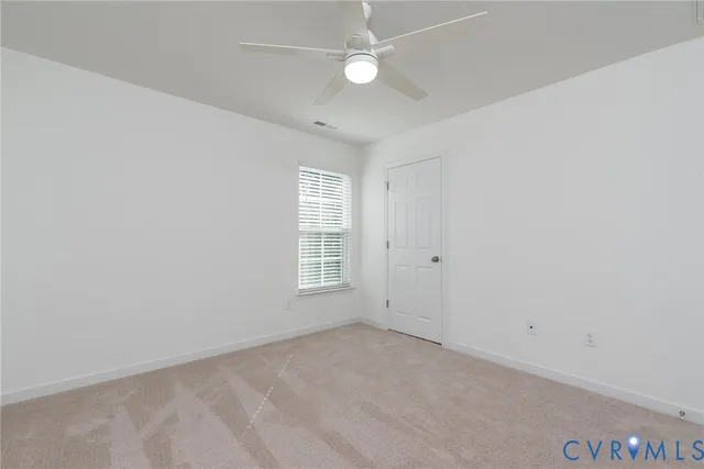 an empty room with a window and ceiling fan