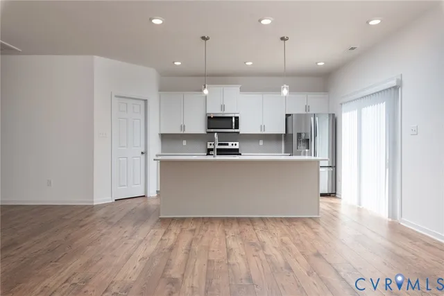 a large kitchen with stainless steel appliances granite countertop a large counter top and a stove with wooden floor