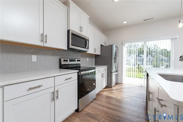 a kitchen with granite countertop white cabinets and stainless steel appliances