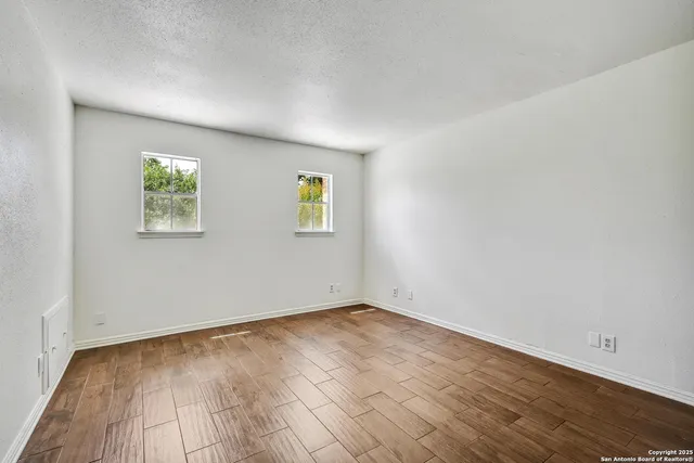 an empty room with wooden floor and window