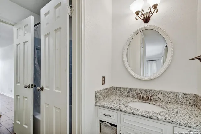 a bathroom with a granite countertop sink and a mirror