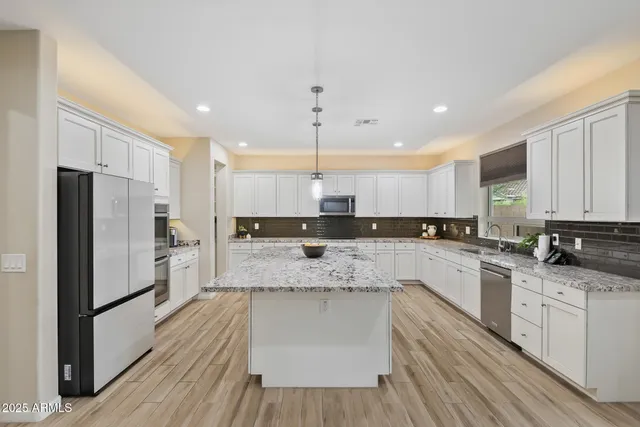 a kitchen with granite countertop white cabinets stainless steel appliances and a sink