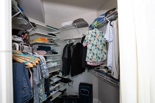 a view of walk in closet with clothes and shoes