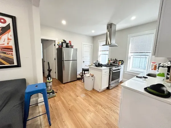a kitchen with refrigerator and wooden floor