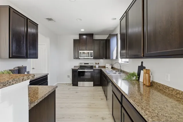 a kitchen with stainless steel appliances granite countertop a sink stove and refrigerator
