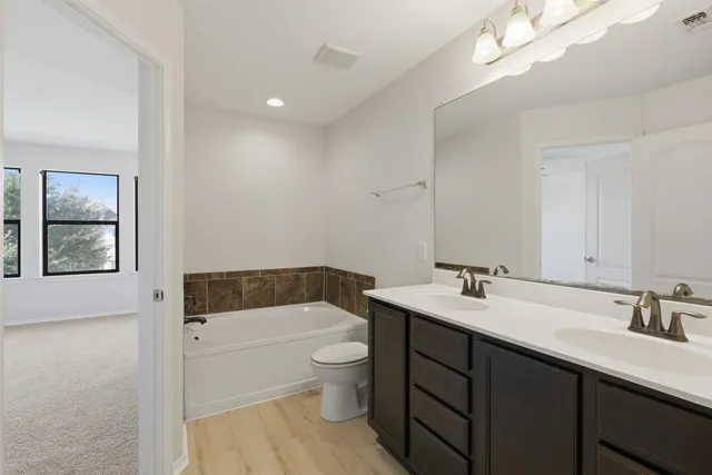 a bathroom with a sink a toilet a mirror and bathtub