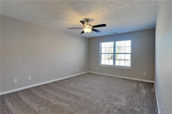 an empty room with windows and fan