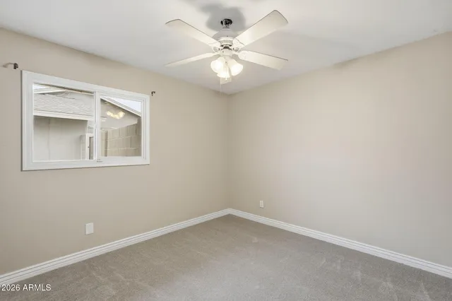 an empty room with a chandelier fan and windows