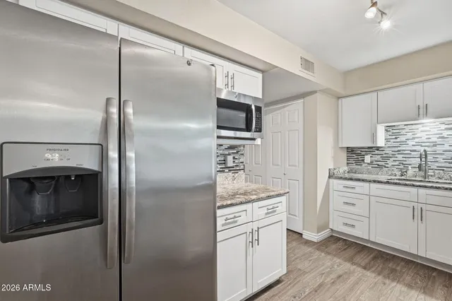 a kitchen with stainless steel appliances kitchen island granite countertop a refrigerator and a stove top oven