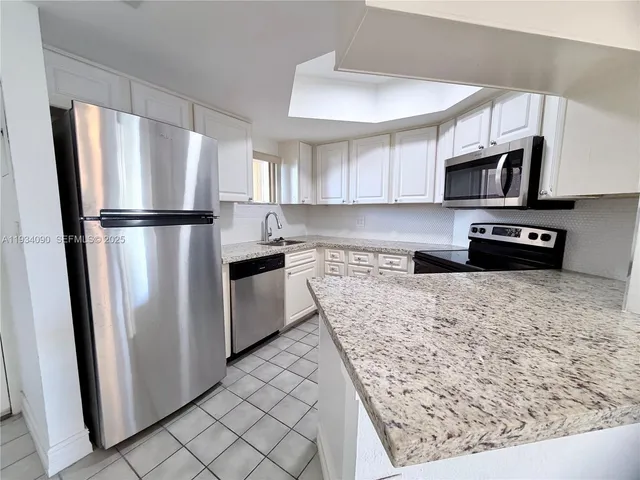 a kitchen with stainless steel appliances granite countertop a refrigerator a stove a sink and a microwave